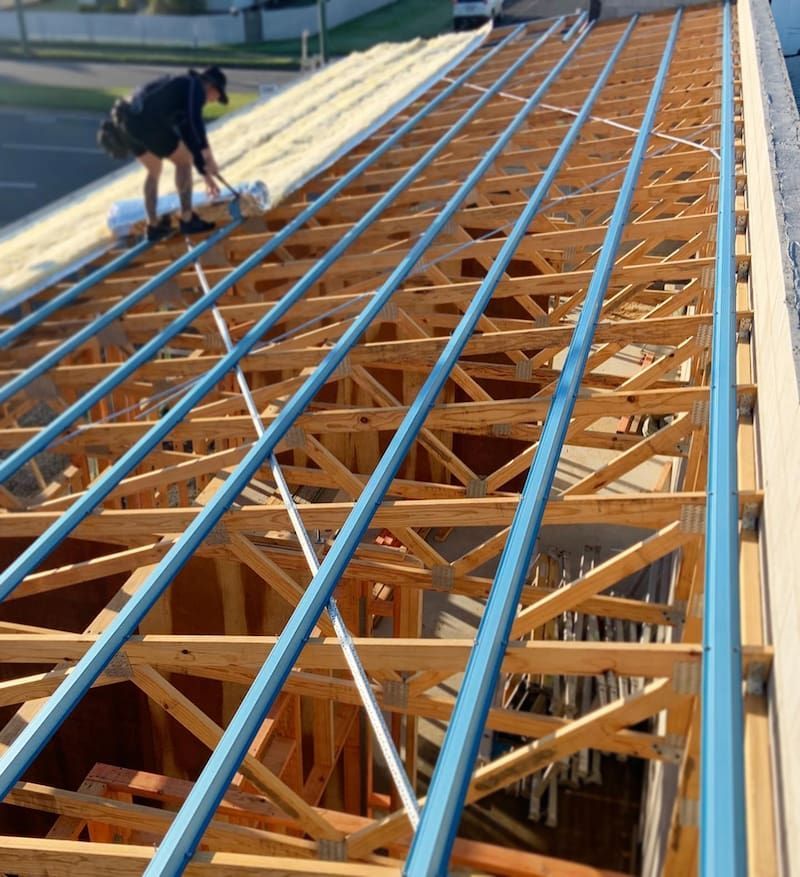 A Man is Working on the Roof of a Building Under Construction — CJM Plumbing & Roofing Mackay in Mackay, QLD