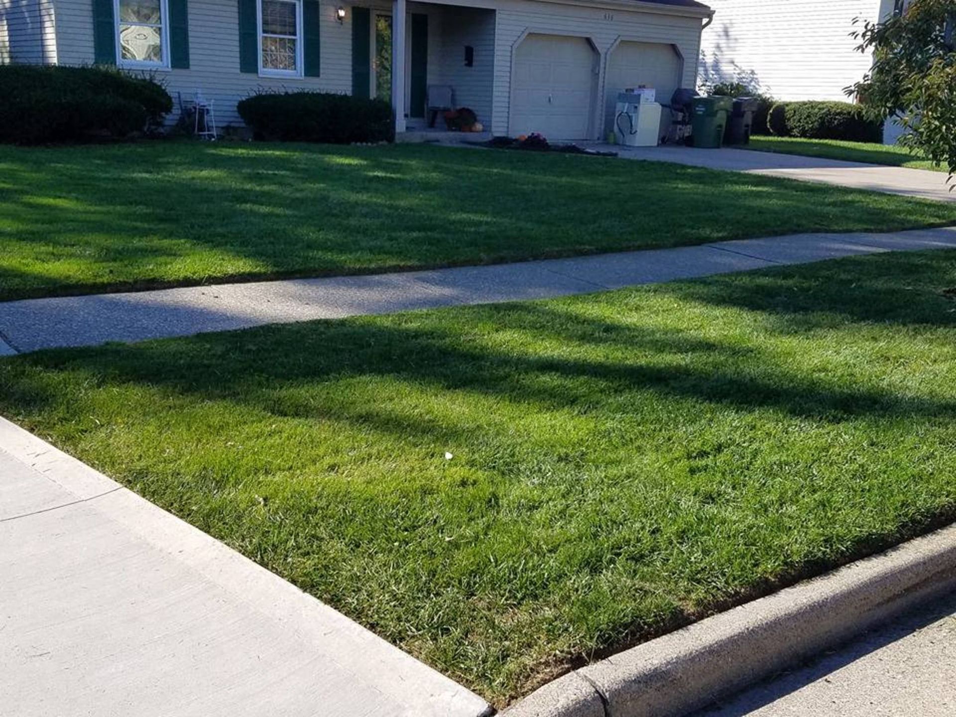 A house with a lush green lawn and a sidewalk in front of it