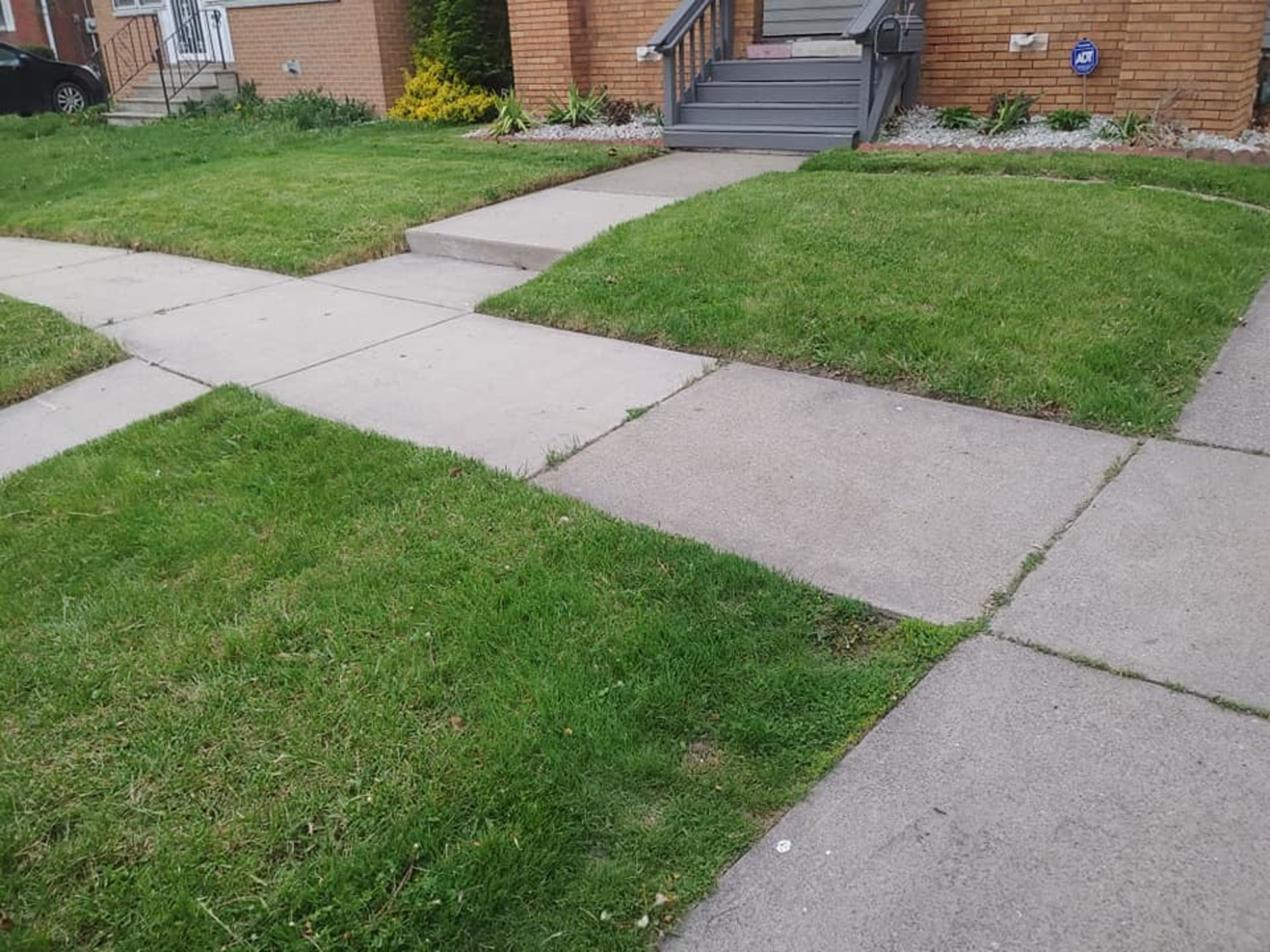A lawn with a concrete walkway leading to a house.