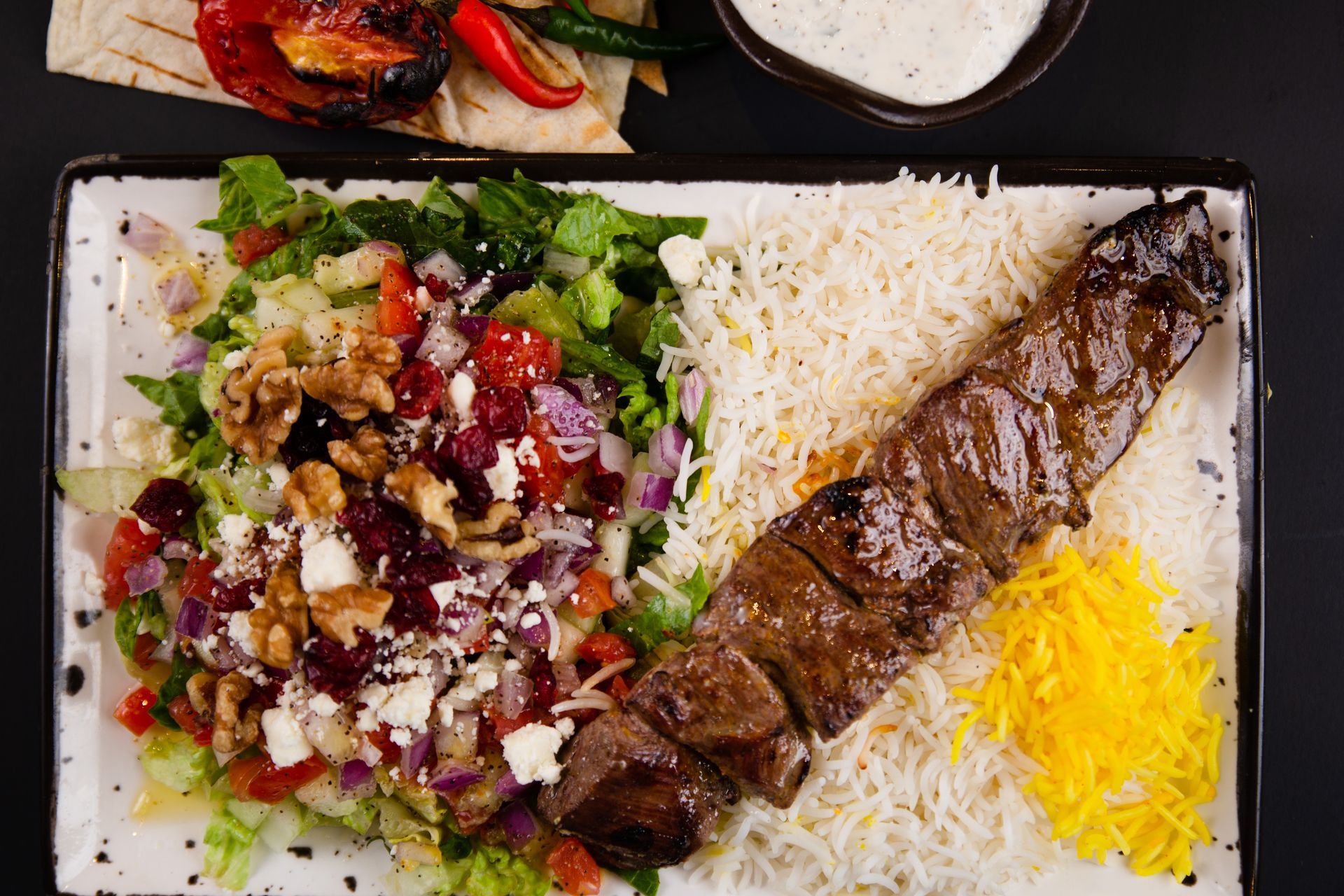 A plate of food with rice , vegetables and meat on a table.