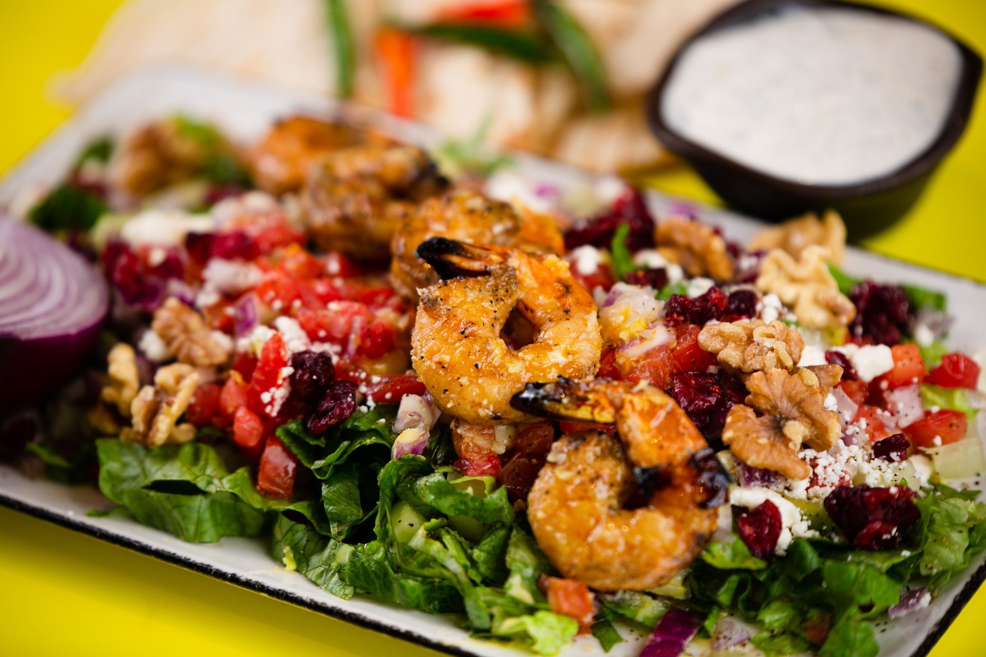 A salad with shrimp , lettuce , tomatoes , onions and walnuts on a plate.