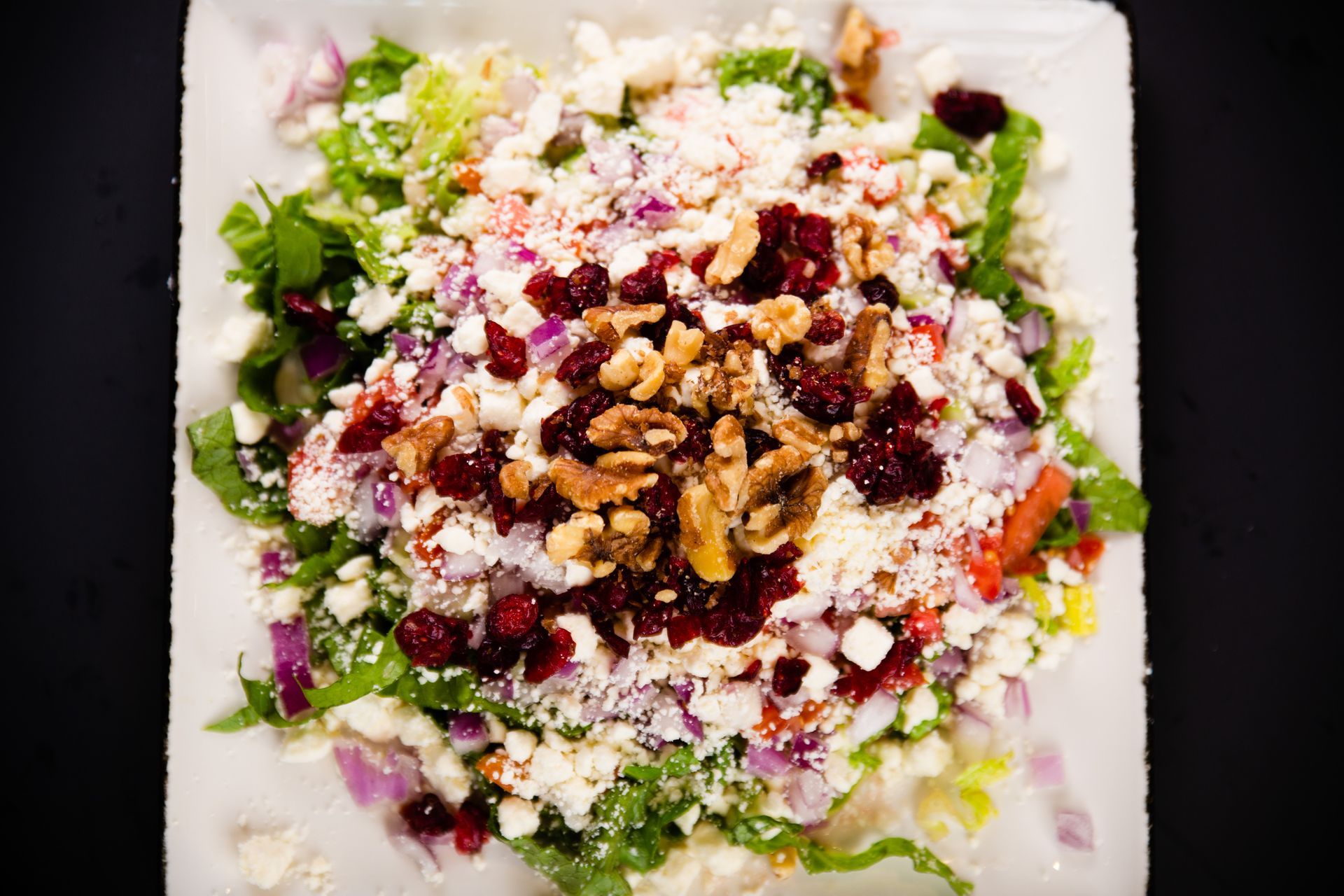 A close up of a salad on a white plate on a table.