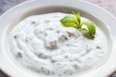 A bowl of yogurt with a mint leaf on top.