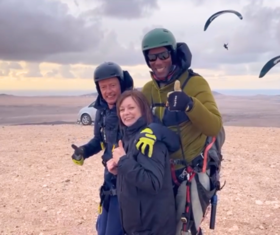 A man wearing a green helmet is giving a thumbs up