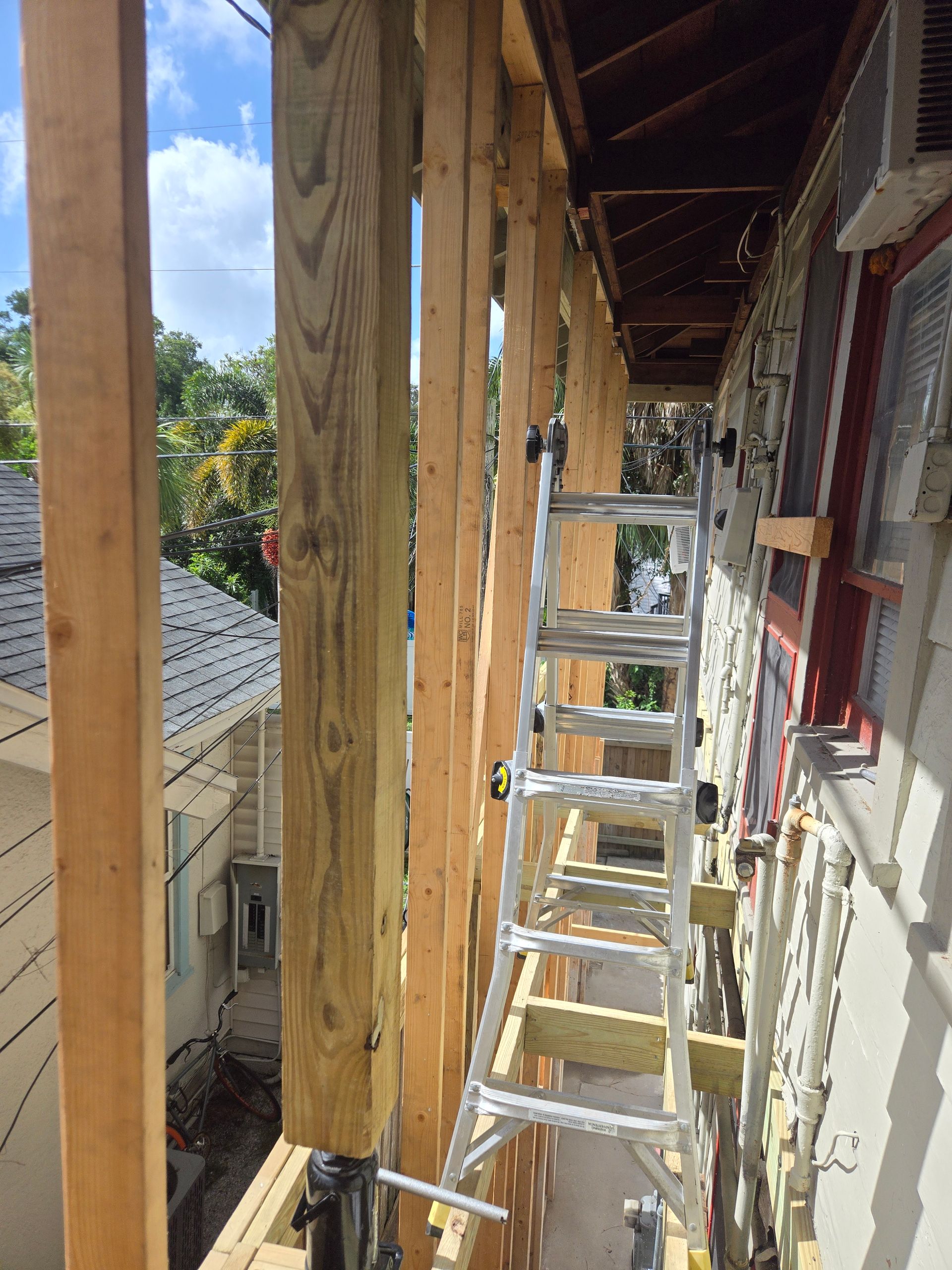 Construction site with wood framing, ladder, and a partially built porch.