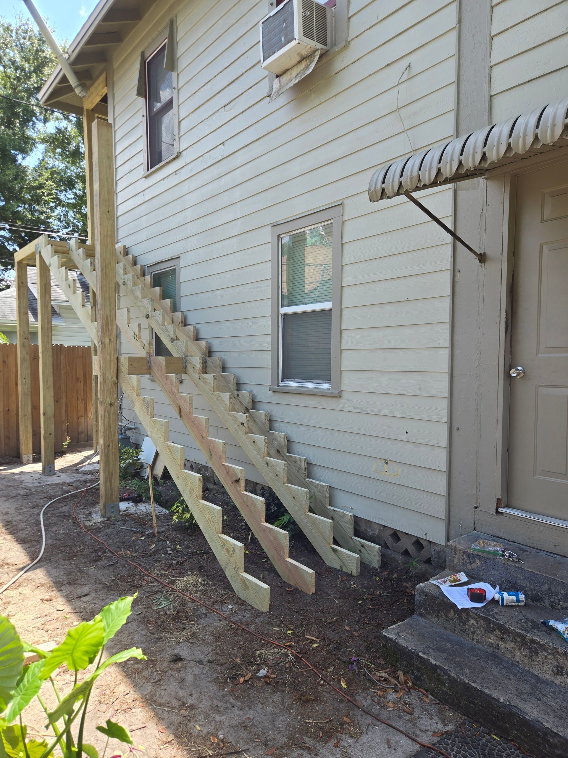 New wooden staircase attached to a two-story building. Construction materials are visible.