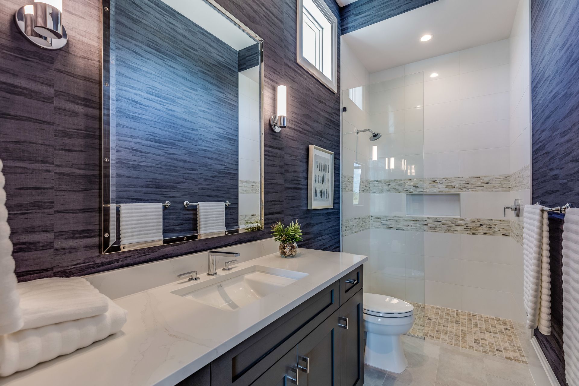 A bathroom with a toilet , sink , mirror and walk in shower.