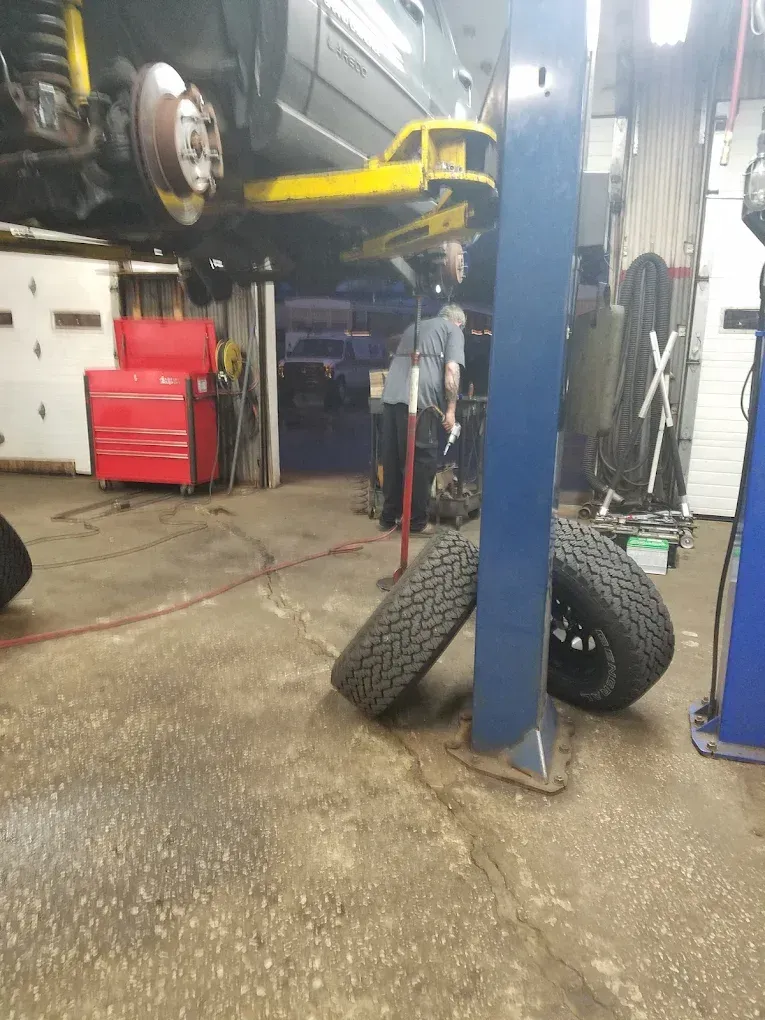 Car on a lift in a garage, tires leaned against a support column.