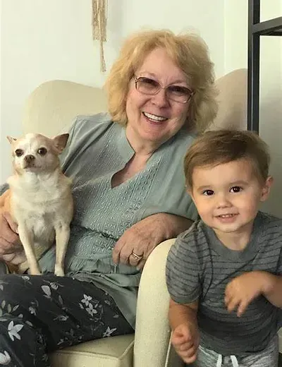 A woman is sitting in a chair with a child and a dog.