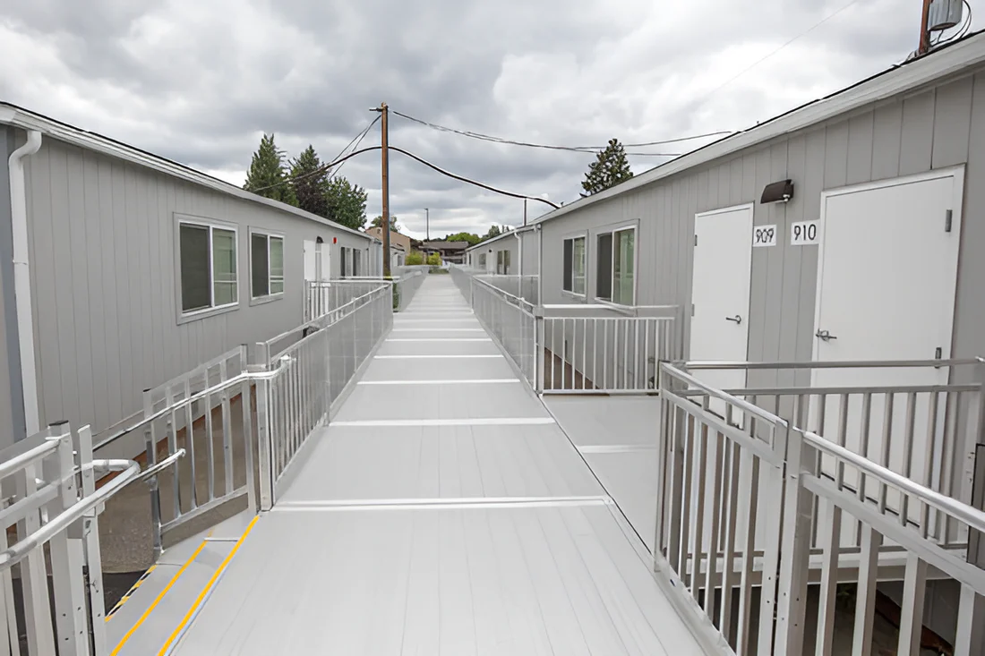 A long walkway between two buildings with a railing.