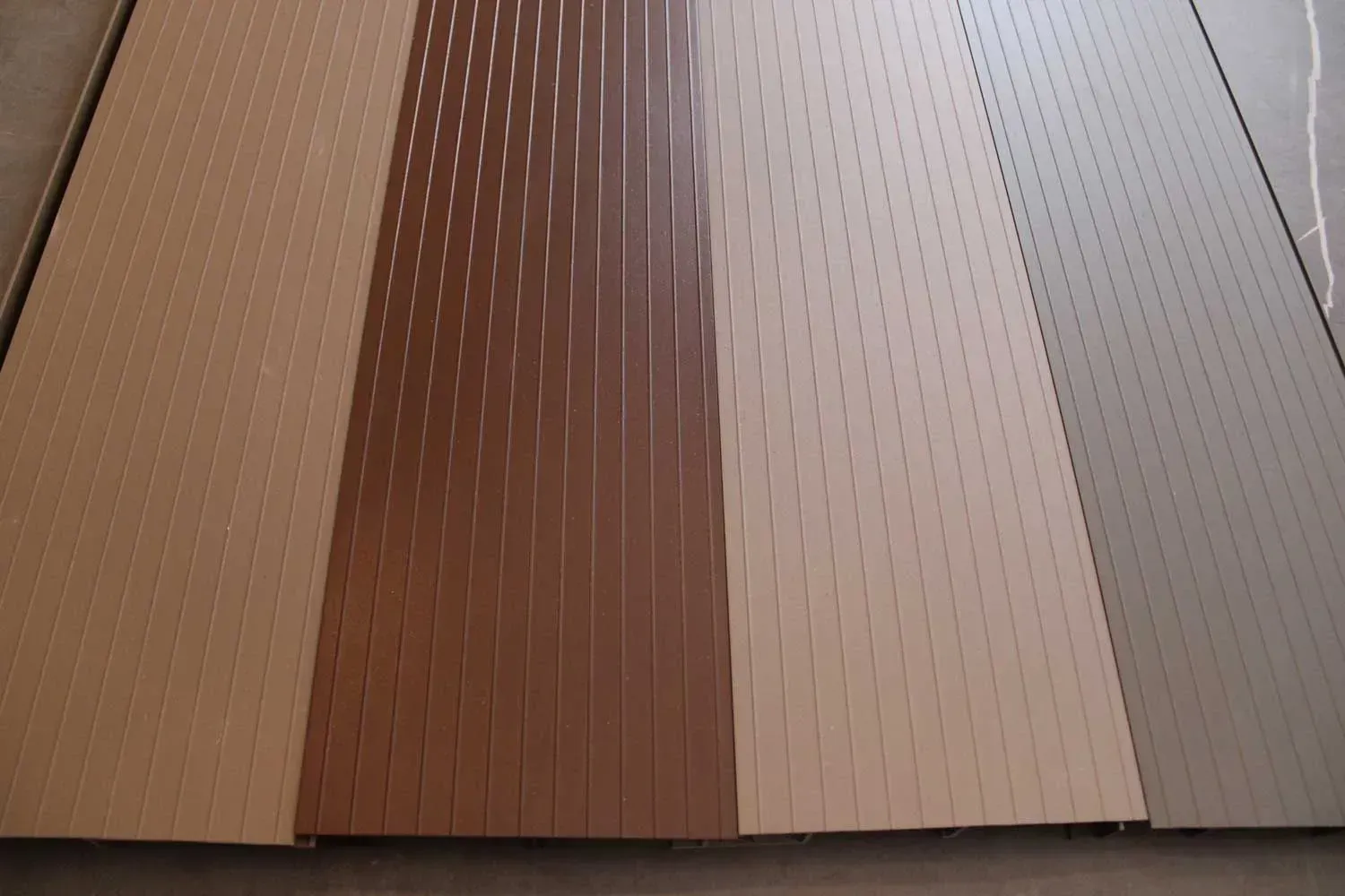 Three different colored sheets of wood are lined up on a table.