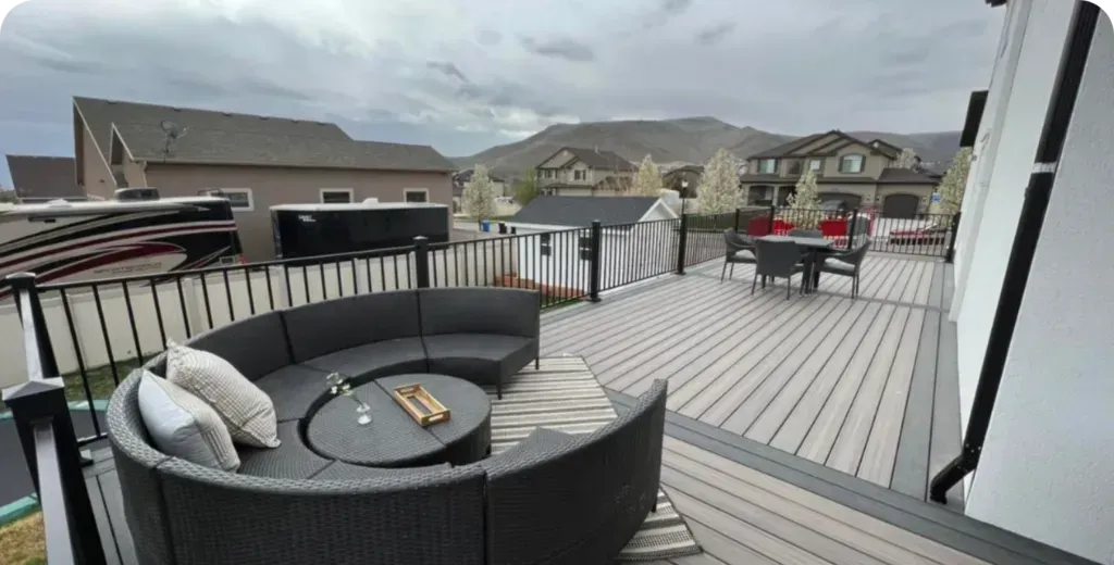 A large deck with a round couch and a table on it.