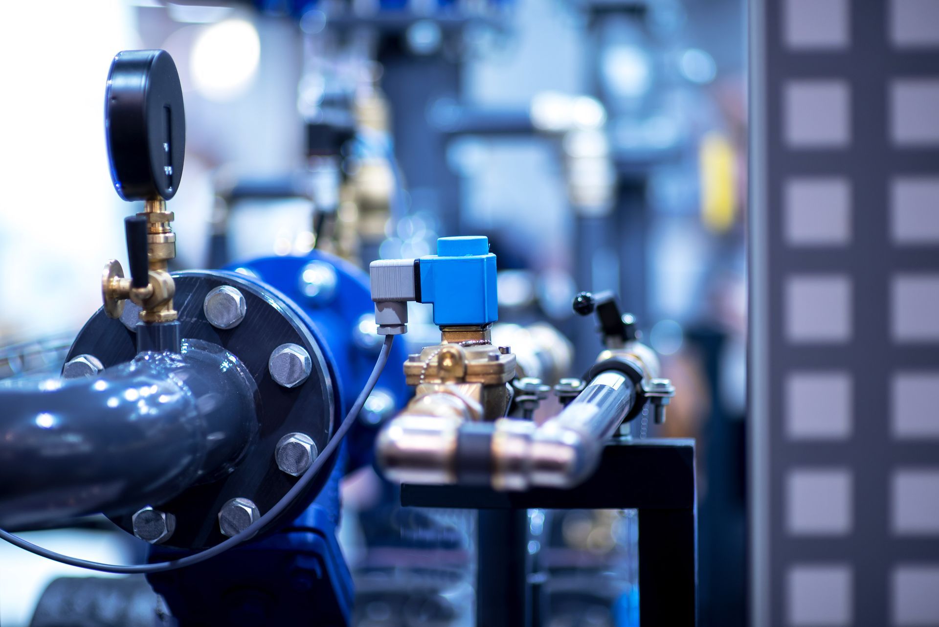 Blue and brass industrial pipes with a pressure gauge and valve.