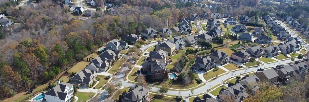 Aerial view of a suburban neighborhood with houses, roads, and trees in autumn.