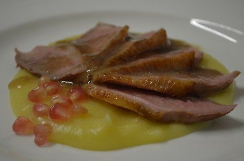 a plate with meat strips, yellow mousse and pomegranate