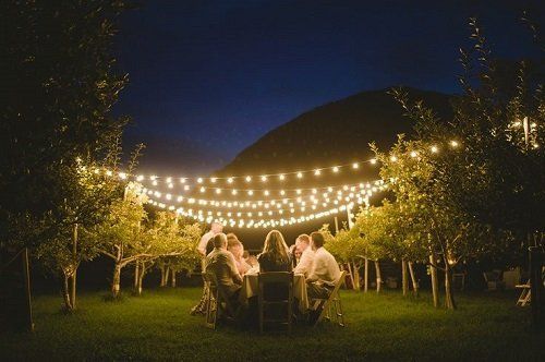 Some people at the table in a garden with decorative lights