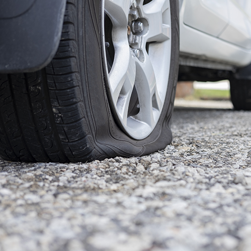 Car tire flat on a gravel surface.