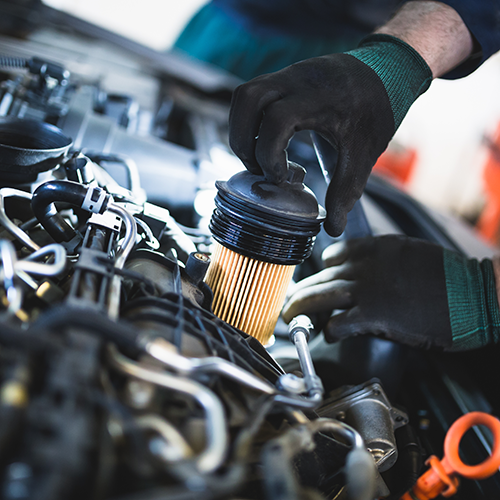 Mechanic in black gloves changing a car oil filter in an engine bay.