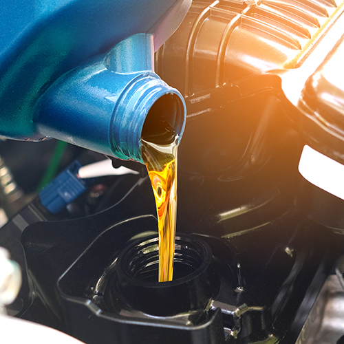 Pouring oil from a blue container into a car engine, highlighting a routine maintenance procedure.