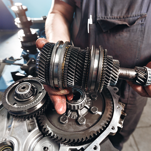 Mechanic holding transmission gears, assembling them inside a metal housing.
