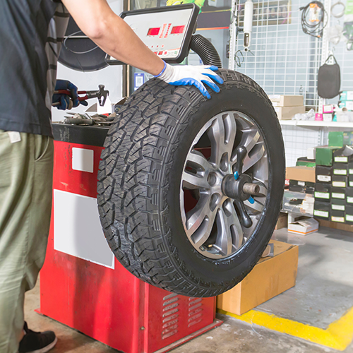 Mechanic balancing a tire on a machine, in a garage.
