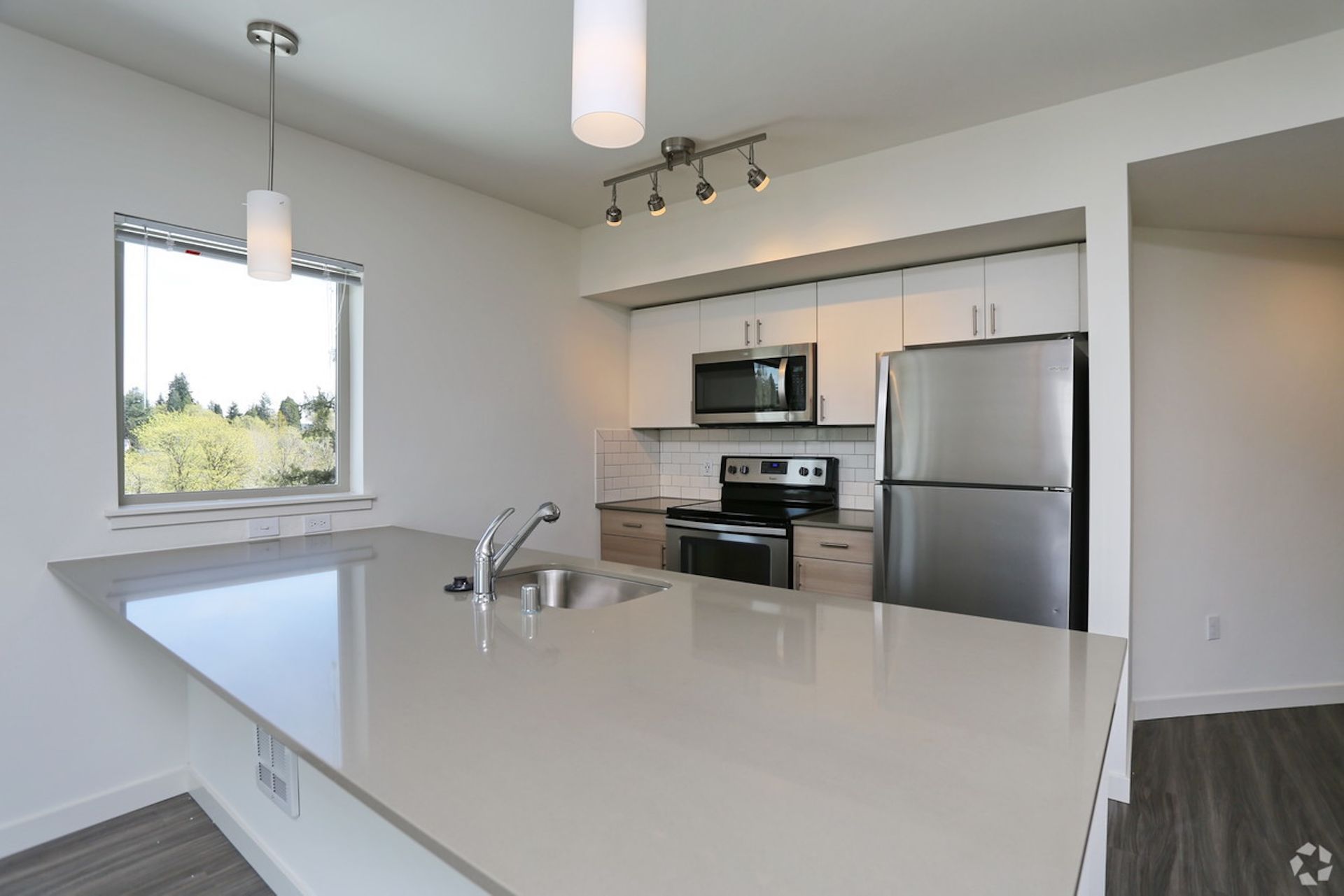 Modern kitchen with stainless steel appliances, large island, and window.