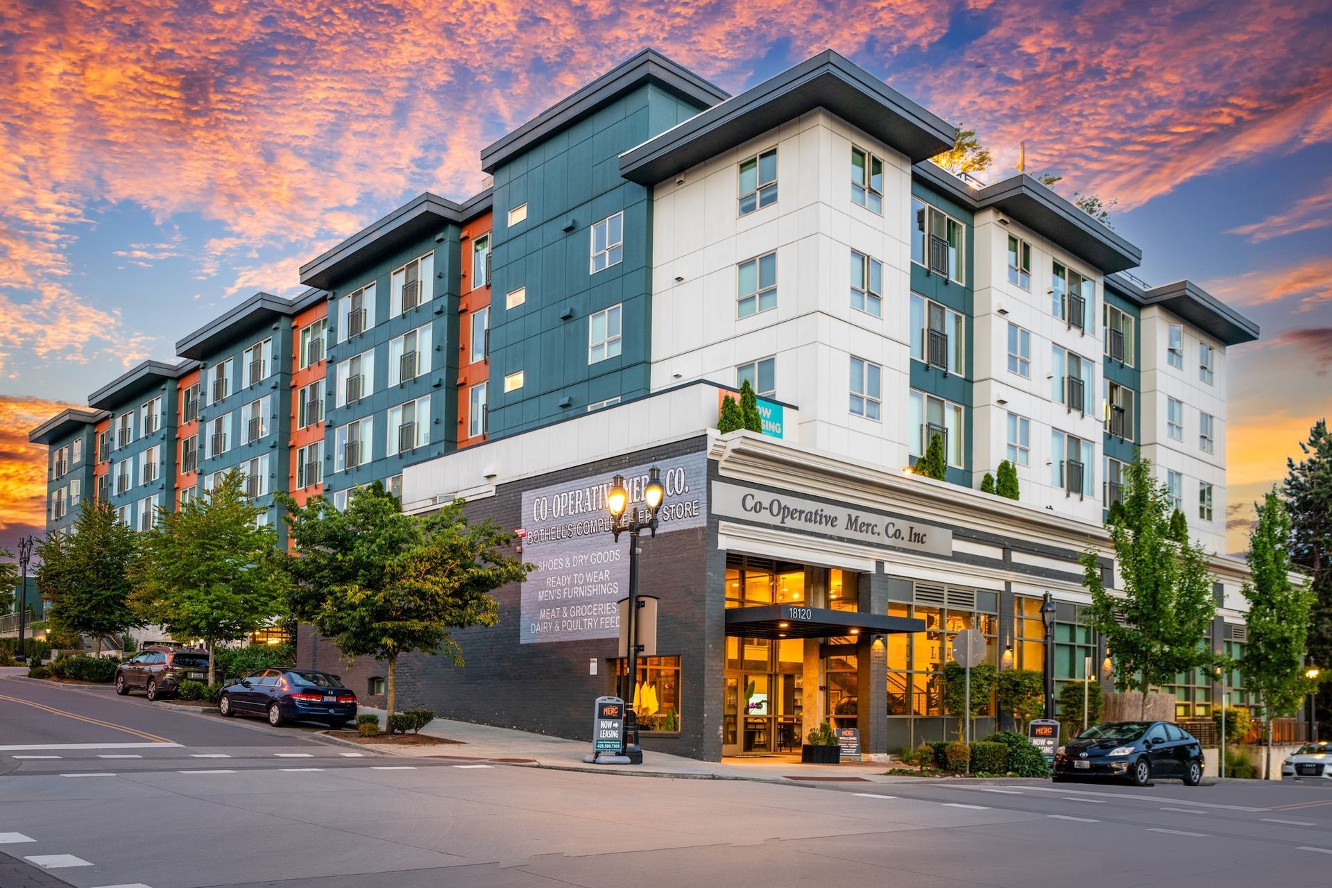 Modern multi-story apartment building with colorful sunset sky.