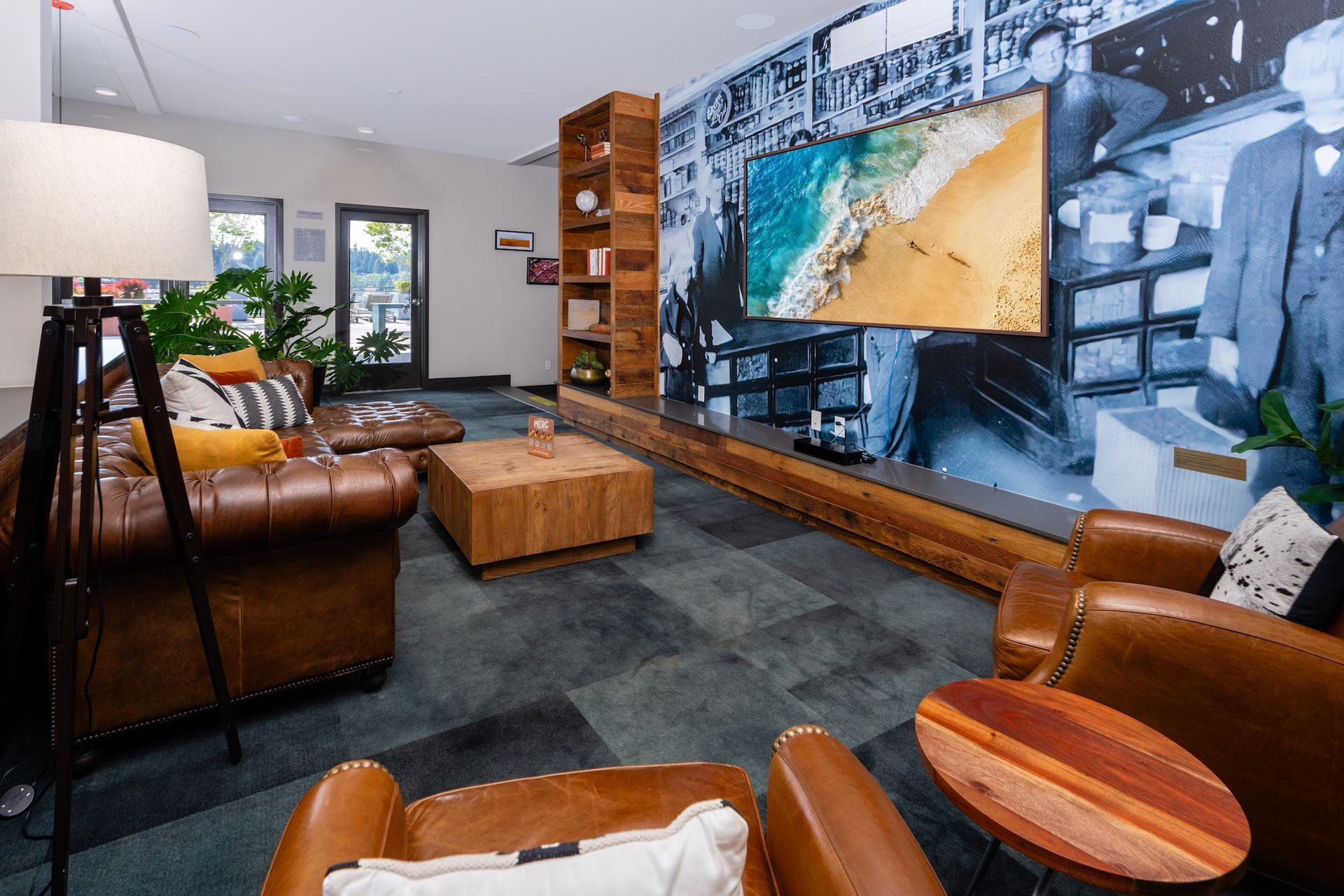 Lounge area with leather furniture, wooden accents, large TV, and a beach scene on the wall.