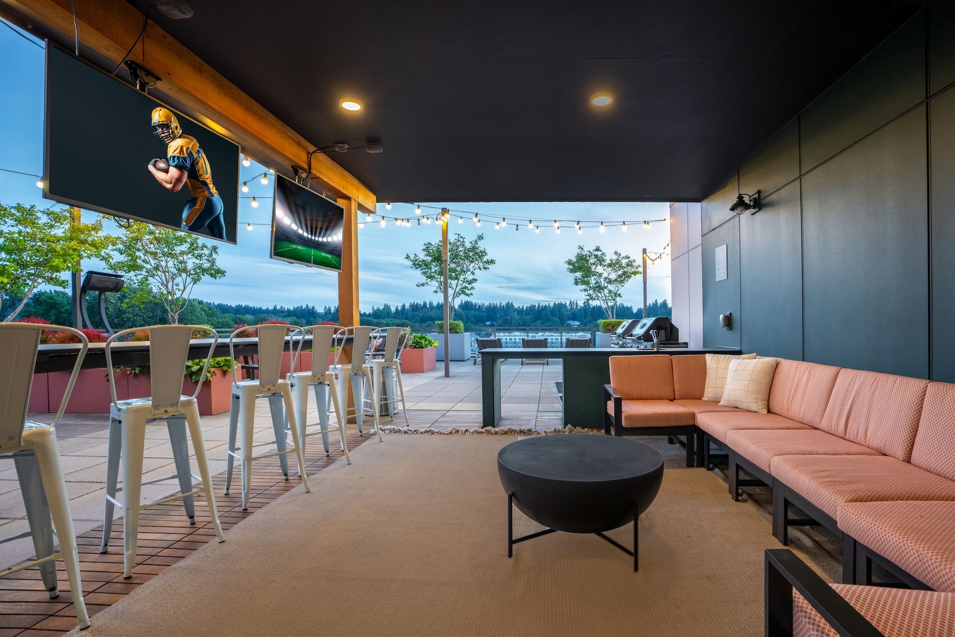 Outdoor bar patio with TVs, bar seating, and a sofa.