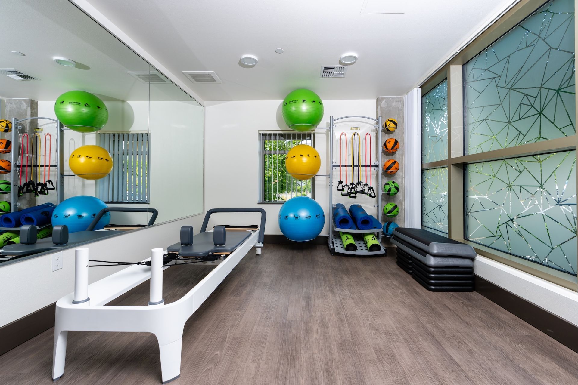 Gym with exercise equipment, including a Pilates reformer, exercise balls, and steps.
