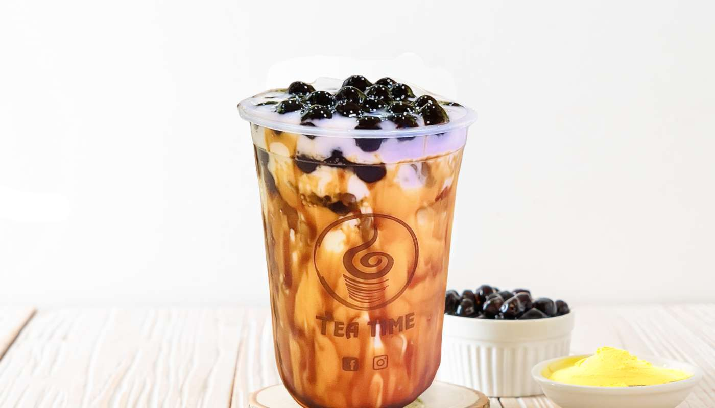 A cup of tea with bubbles on top of it on a table.