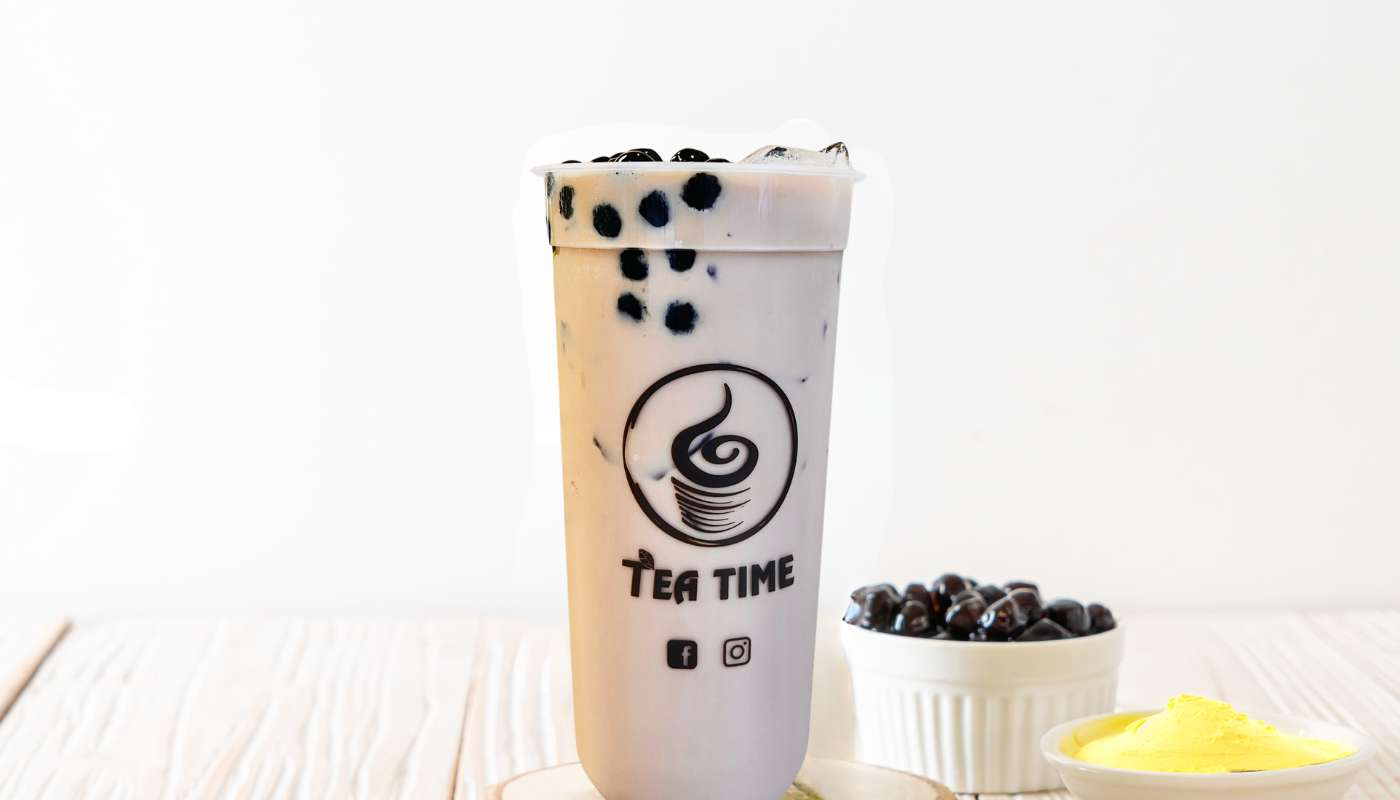 A cup of tea is sitting on a table next to a bowl of bubbles.