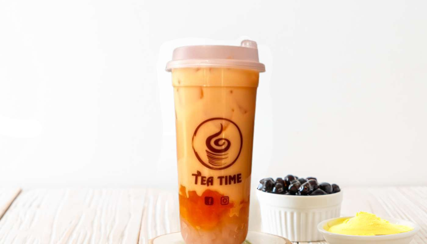 A cup of tea is sitting on a table next to a bowl of blueberries.