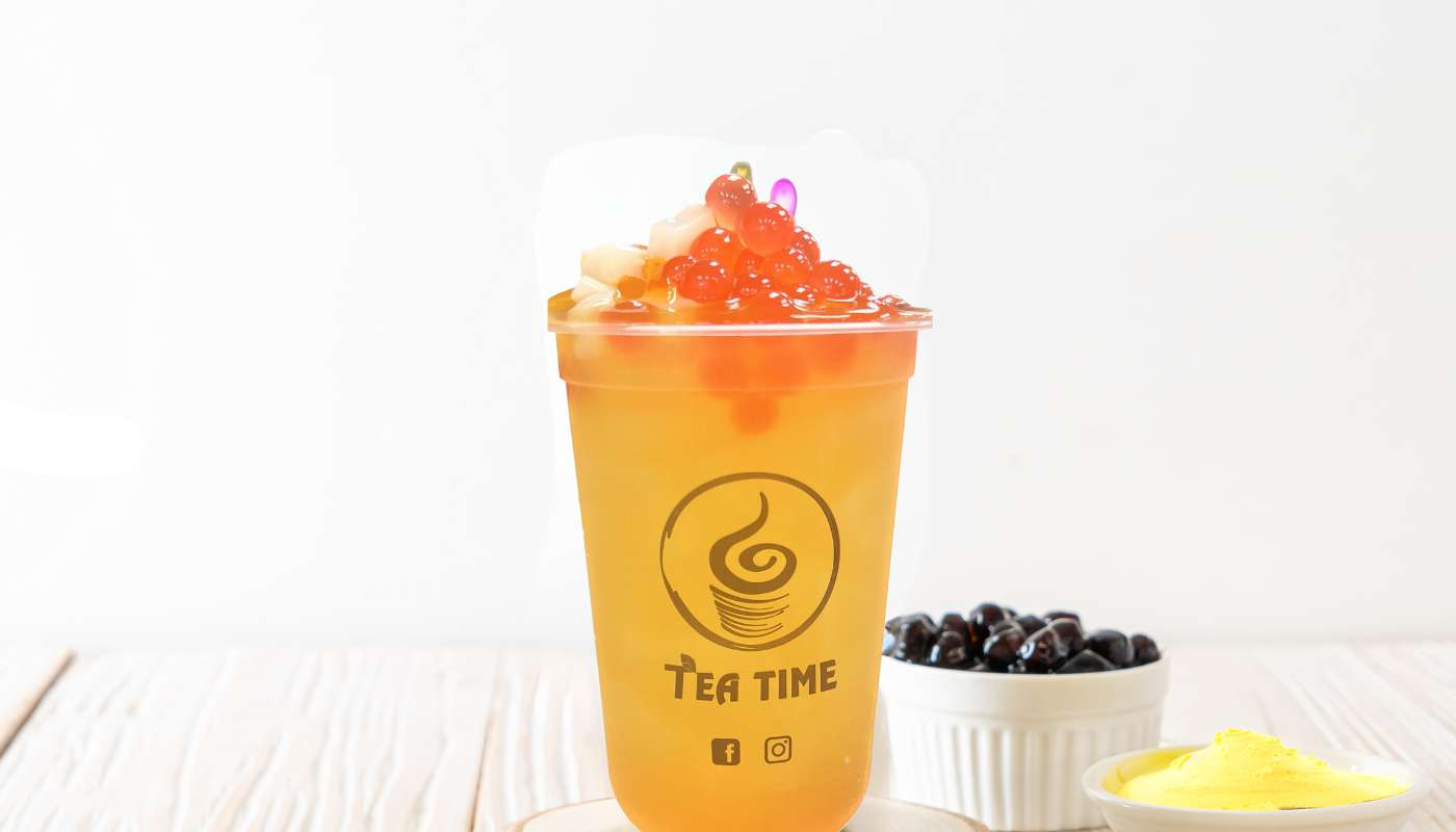 A cup of tea is sitting on a wooden table next to a bowl of blueberries.