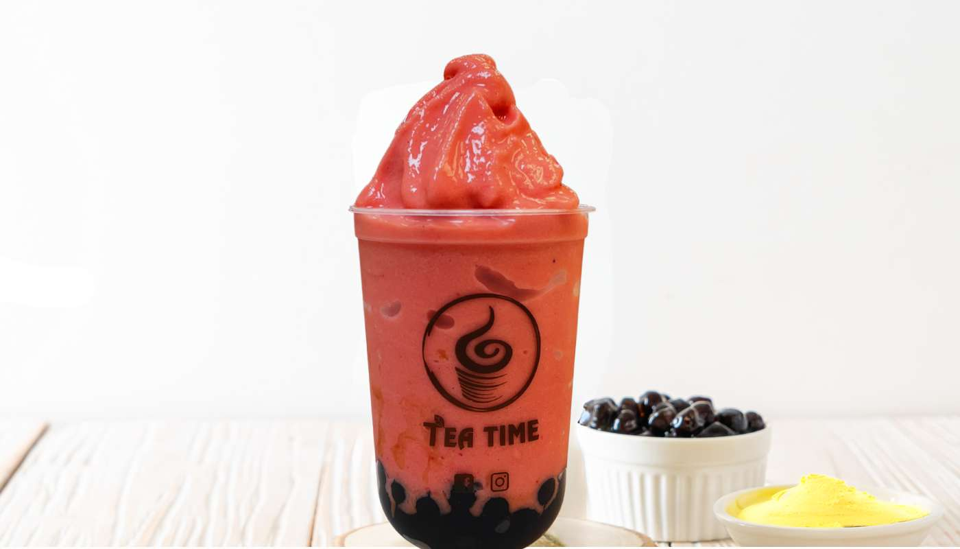 A strawberry smoothie in a cup on a table.