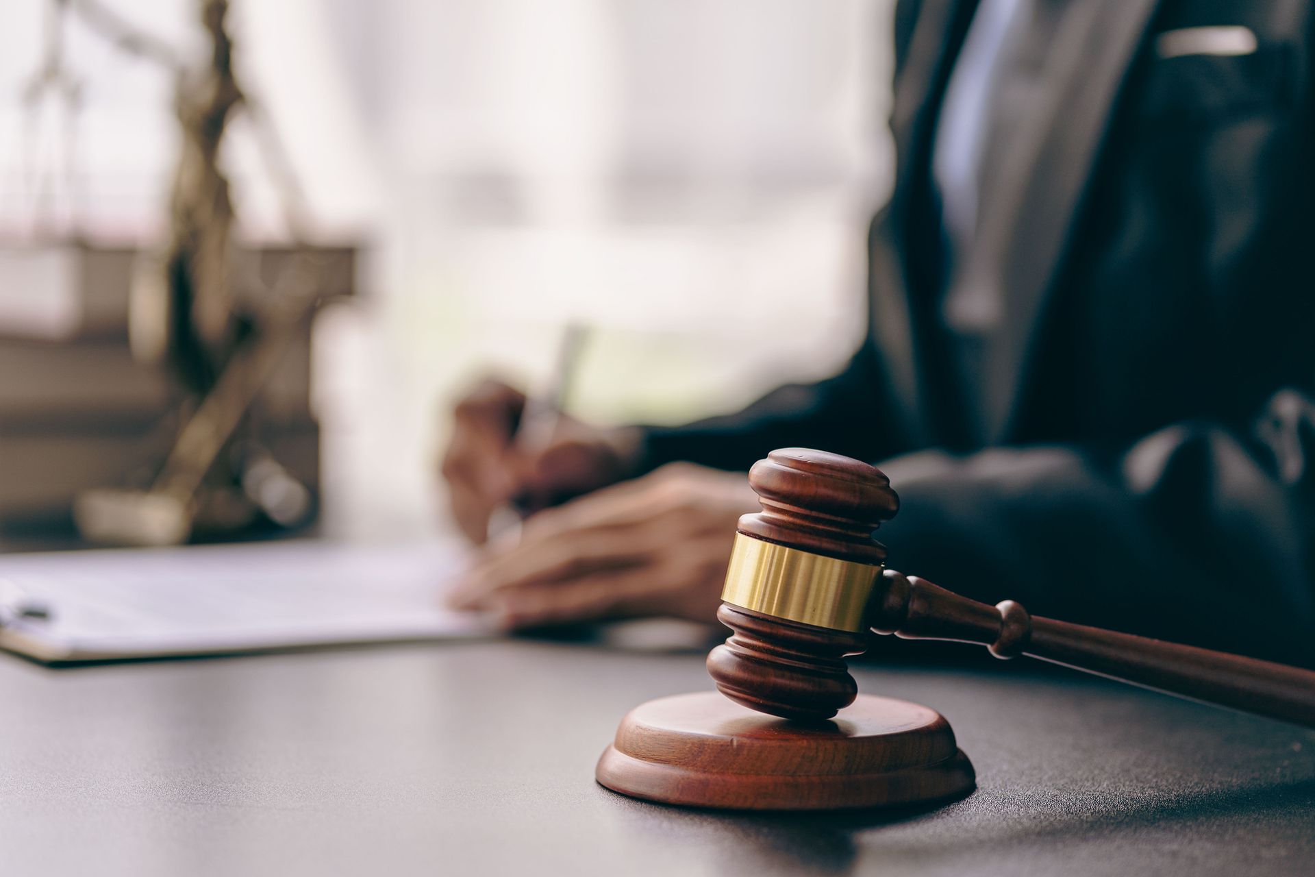 A judge is sitting at a table with a gavel in front of him.