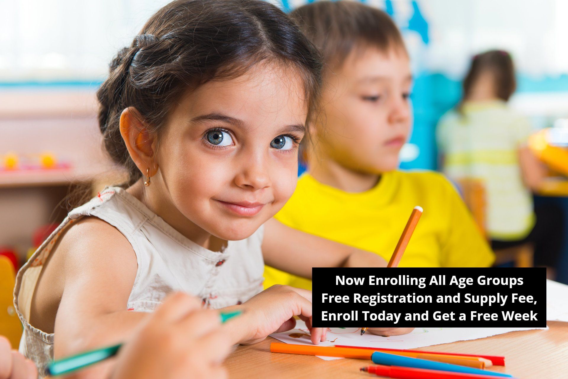 A little girl is sitting at a table with a pencil in her hand.