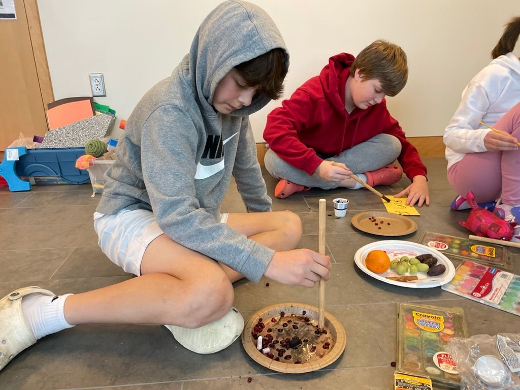 A group of children are sitting on the floor with plates of food.