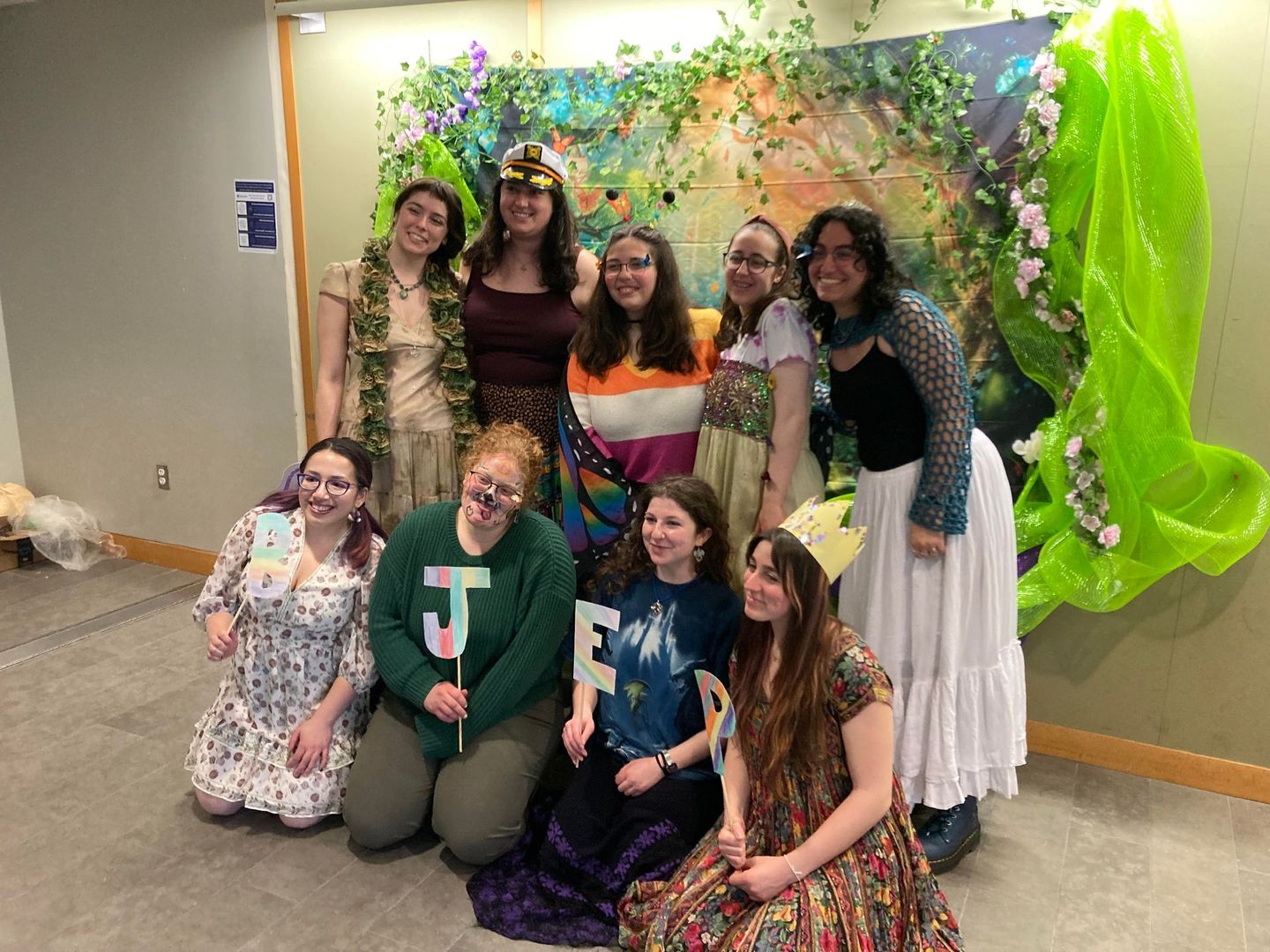 A group of women are posing for a picture in front of a painting.