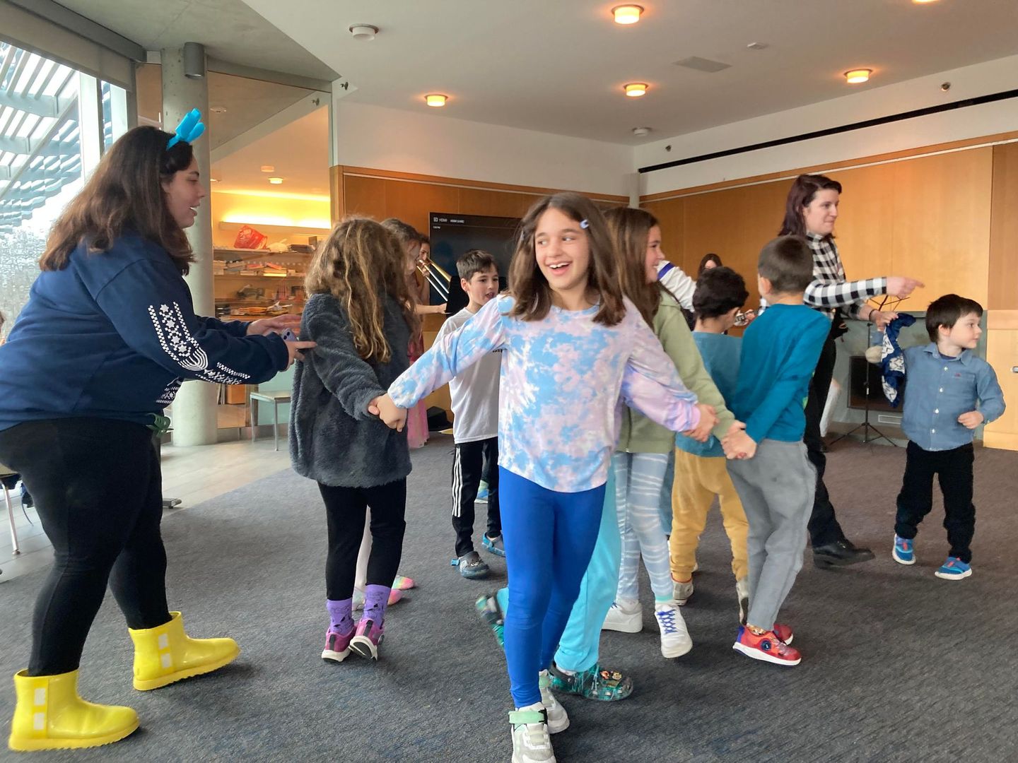 A group of children are holding hands and dancing in a room.