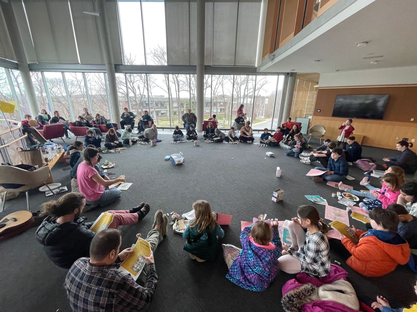 A group of people are sitting in a circle on the floor in a room.