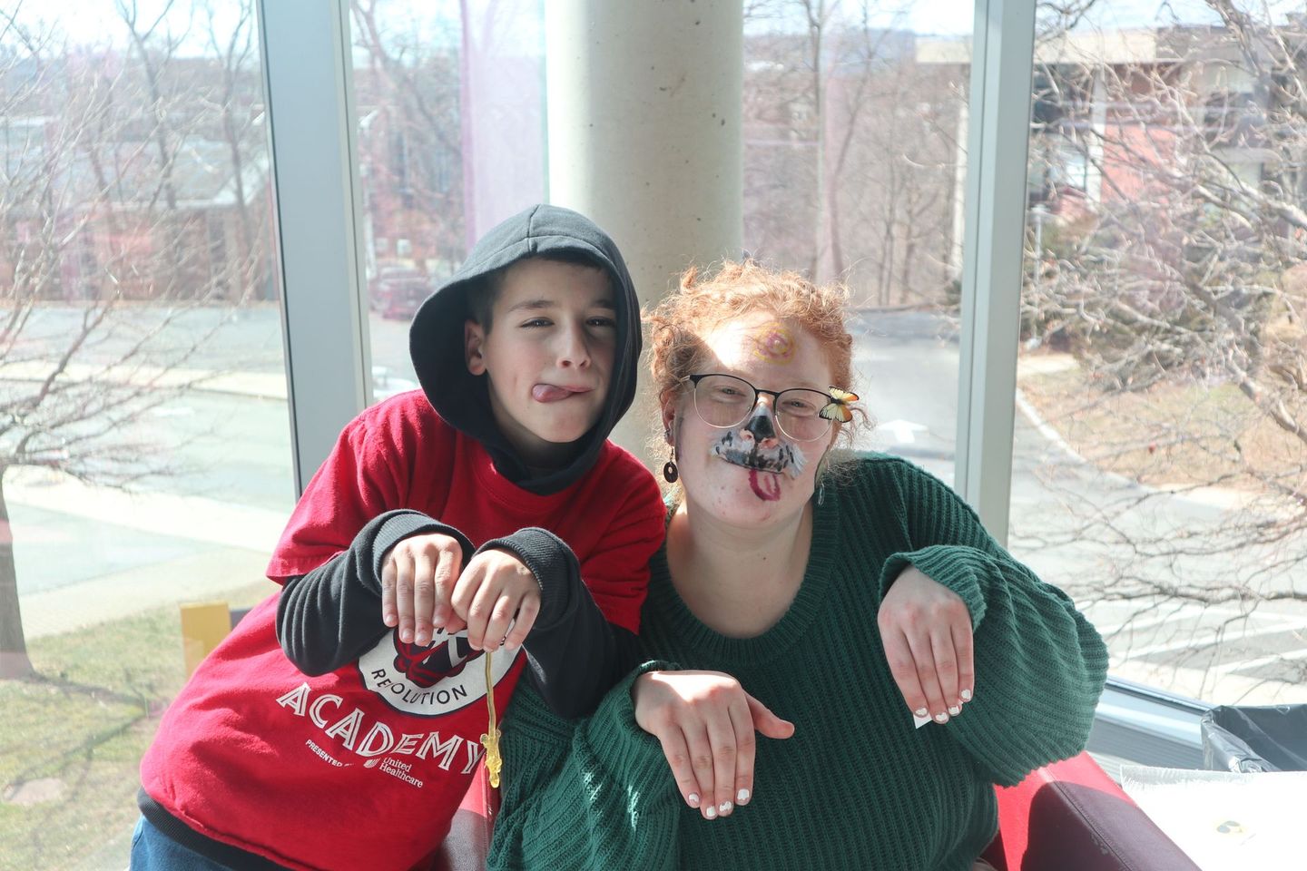 A boy and a girl are posing for a picture and the boy is wearing a red shirt that says academy