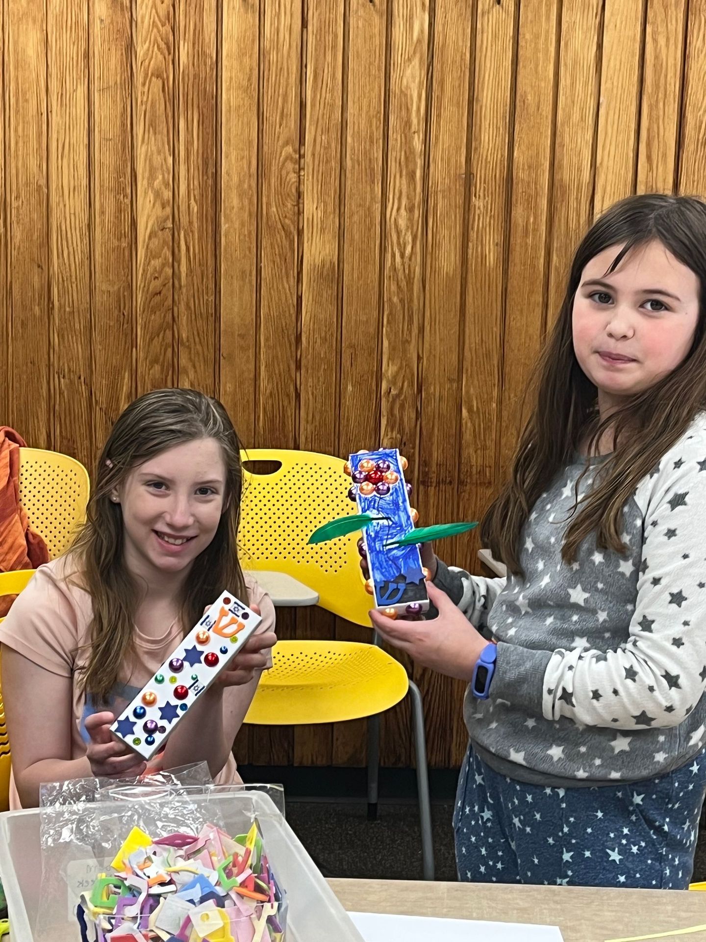 Two young girls are standing next to each other holding a toy.