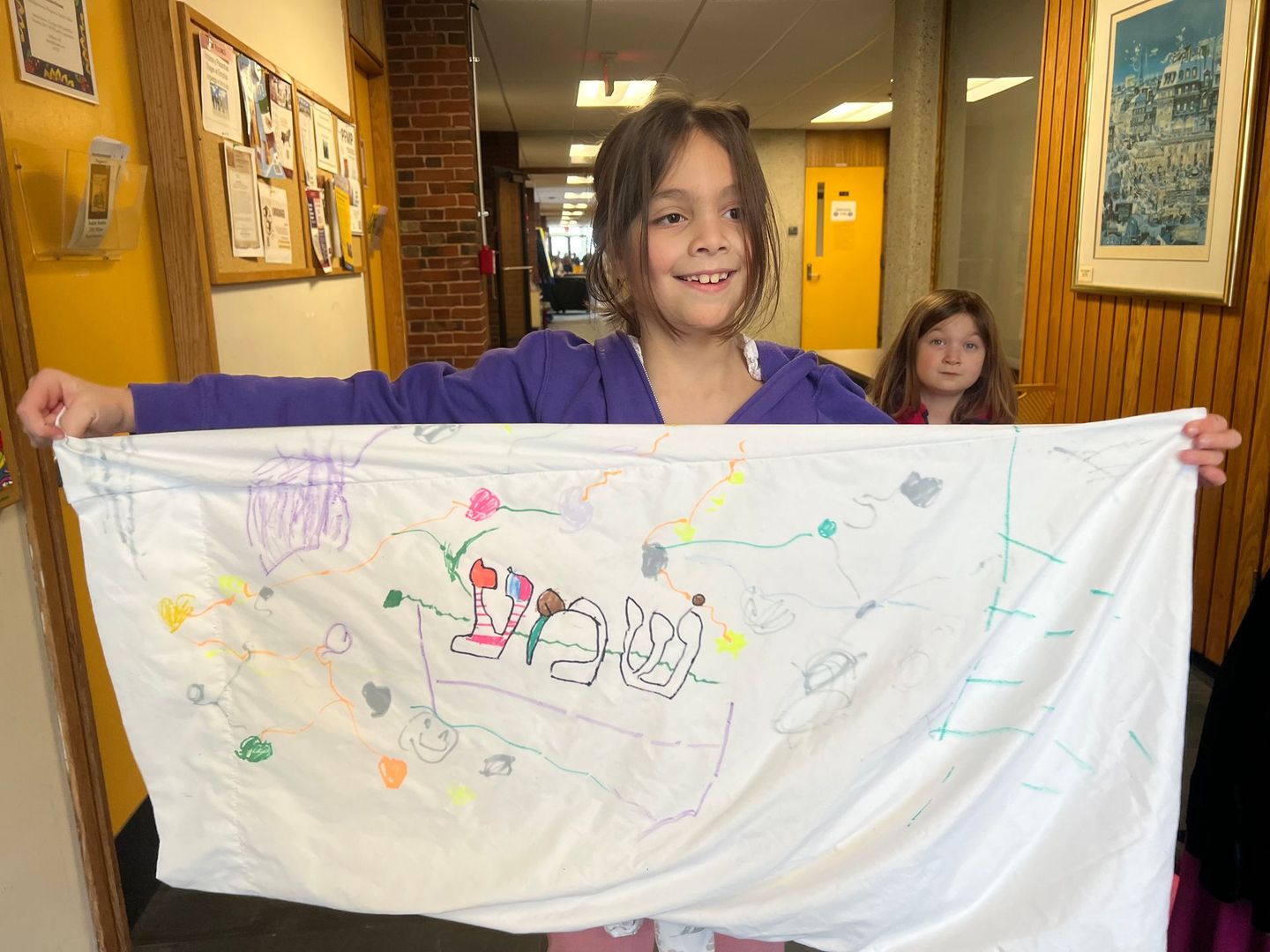 A girl in a purple shirt is holding a piece of paper that says ' i love you ' on it.