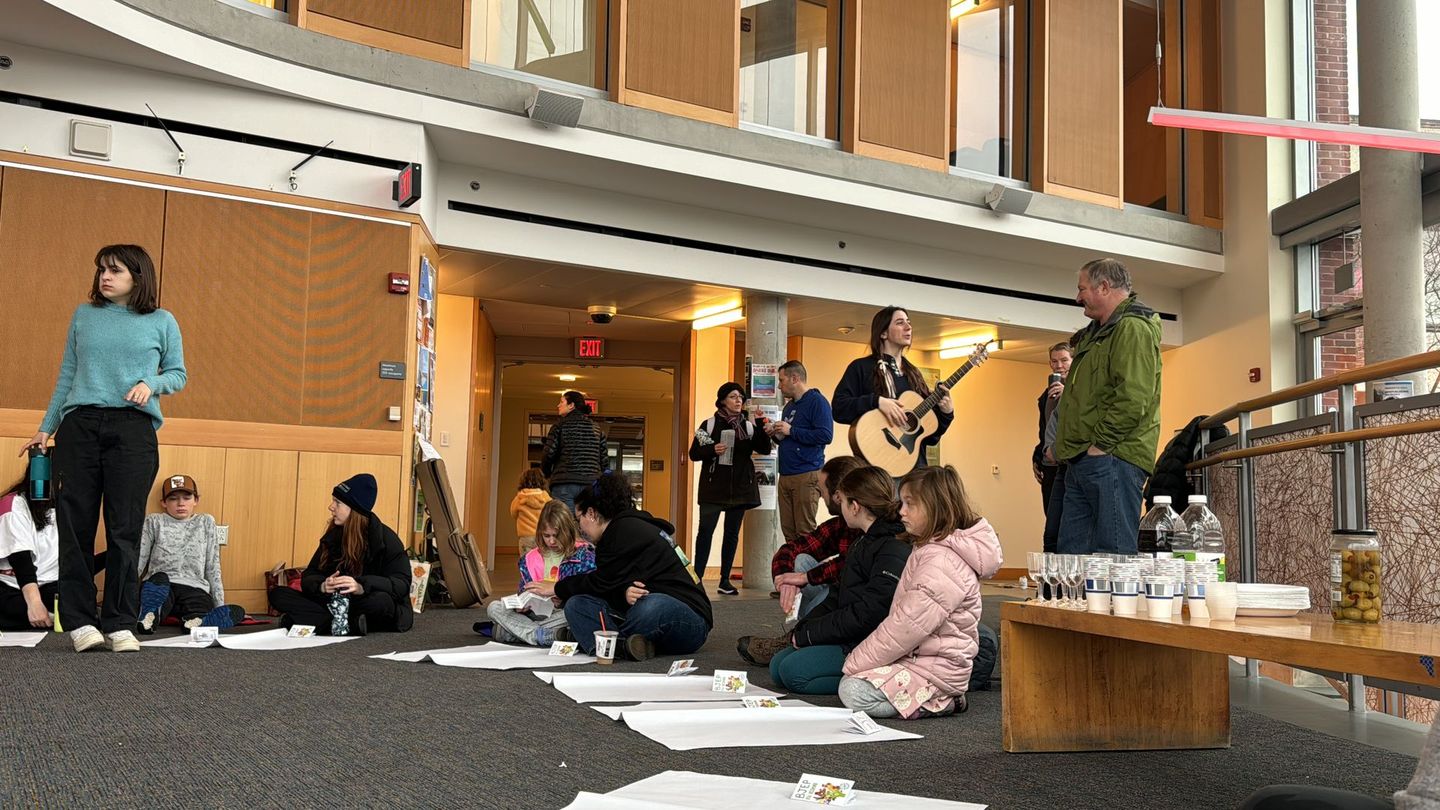 A group of people are sitting on the floor in a large room.