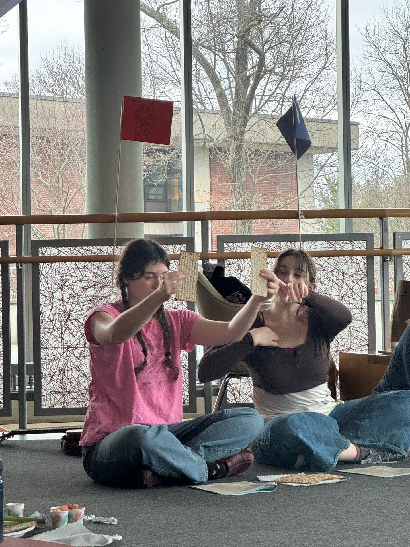 Two women are sitting on the floor in front of a window.