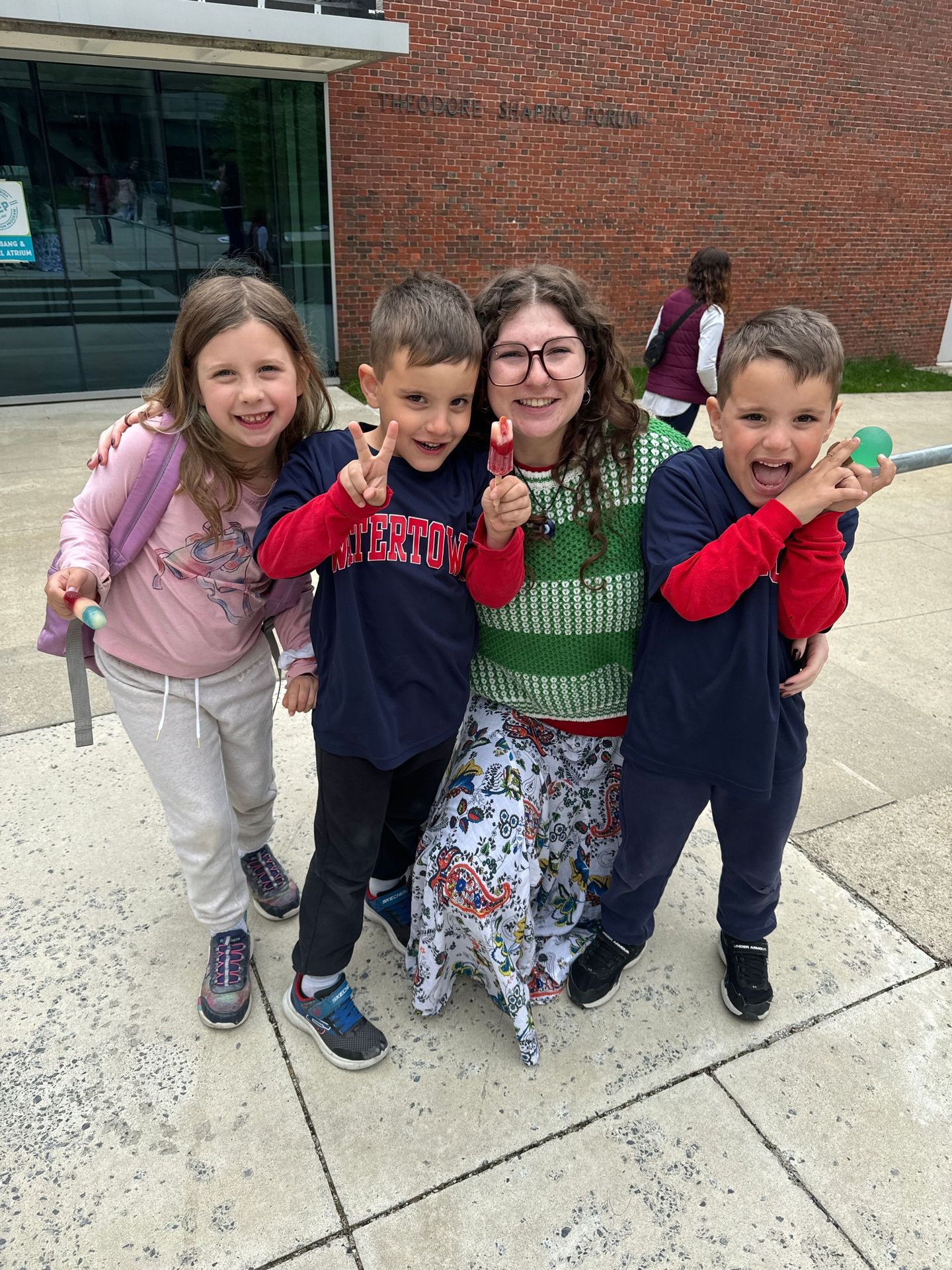 A group of children standing next to each other on a sidewalk.