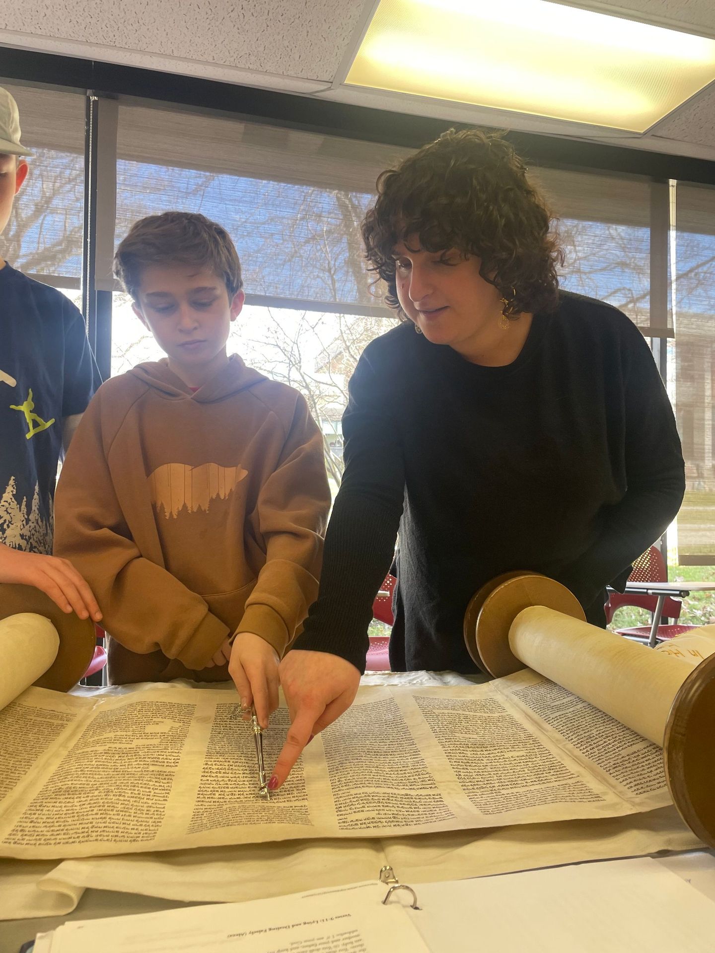 A group of young men are looking at a scroll of the torah.