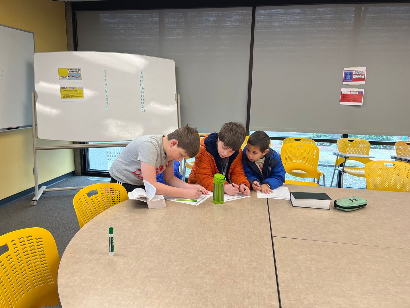 A group of young boys are sitting at a table in a classroom.