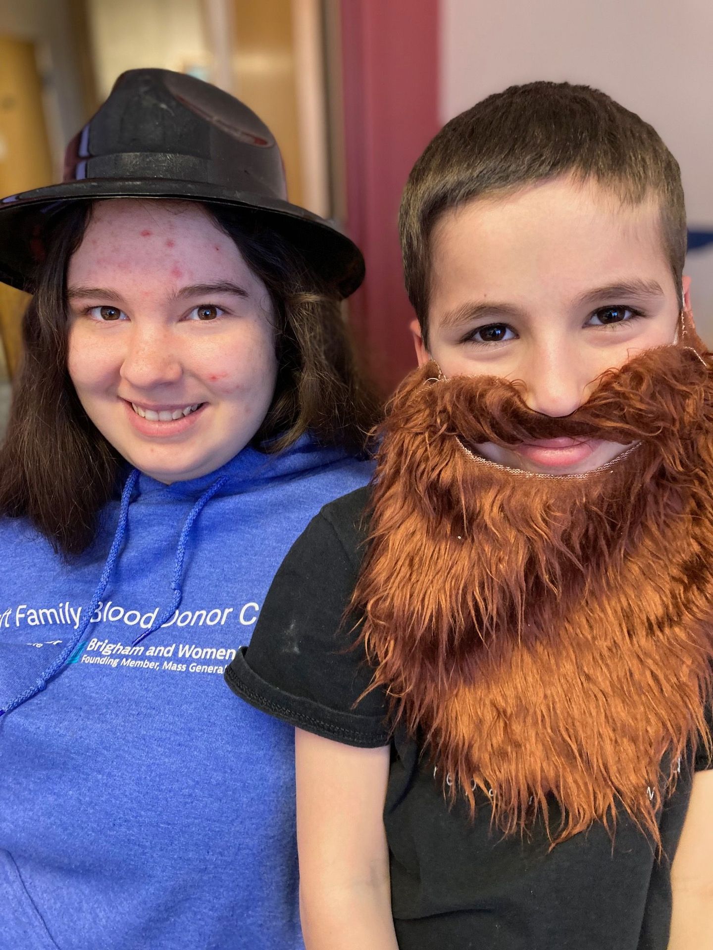 A boy and a girl wearing fake beards are posing for a picture.